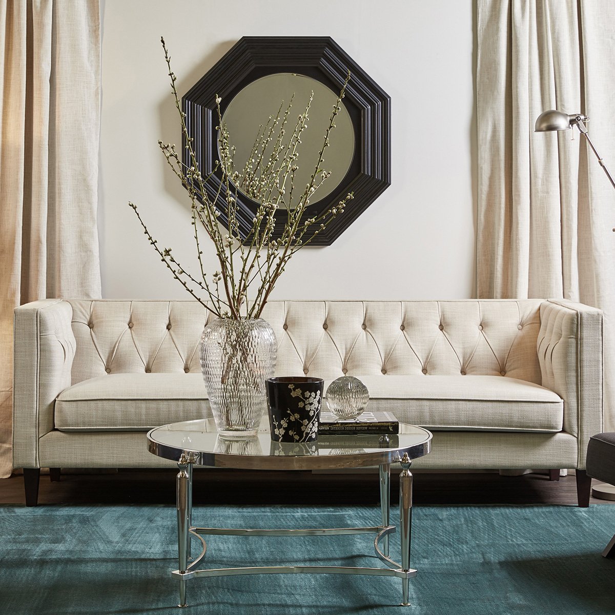A tufted sofa with a natural linen upholstery in a living room setting, featuring black timber legs and button-tufted backrest.
